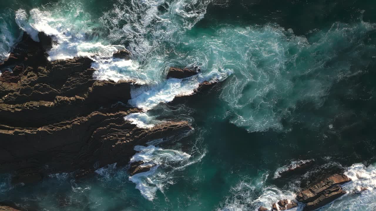 Ocean cliffs of Portugal coast, rocky reefs and crashing waves, drone top down view