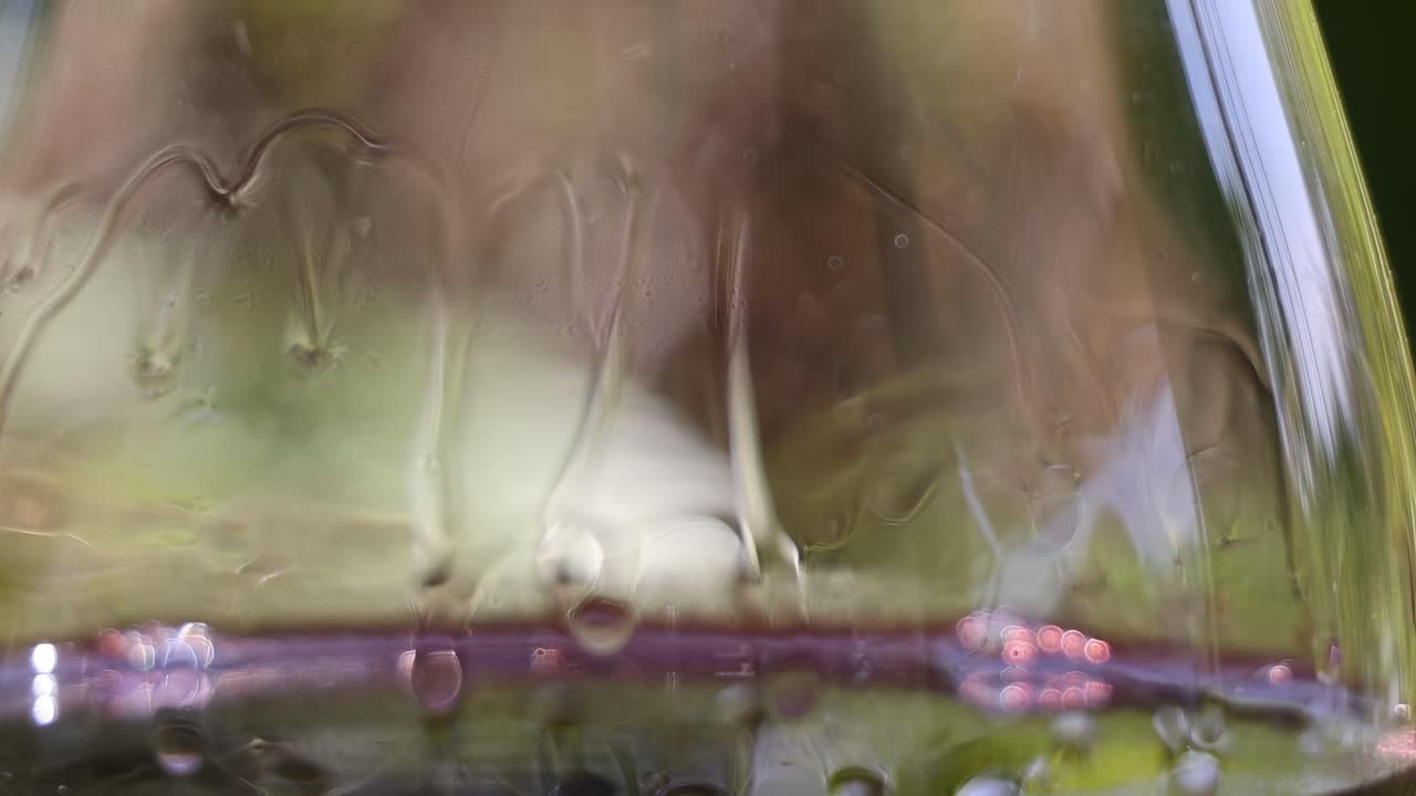 Detailed view of wine legs forming on the inside of a glass, showcasing fluid dynamics.