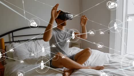 Animation-of-network-of-connections-with-icons-over-man-wearing-vr-headset