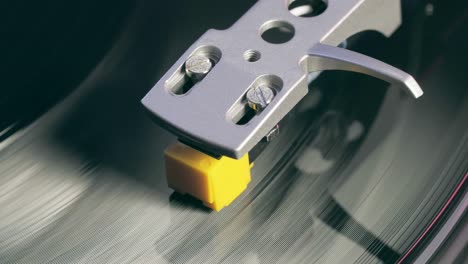 Vinyl player turntable. A fragment of a rotating vinyl record, a stylus with a needle close-up. Stopping a needle and a vinyl plate close-up. Macro. View from above