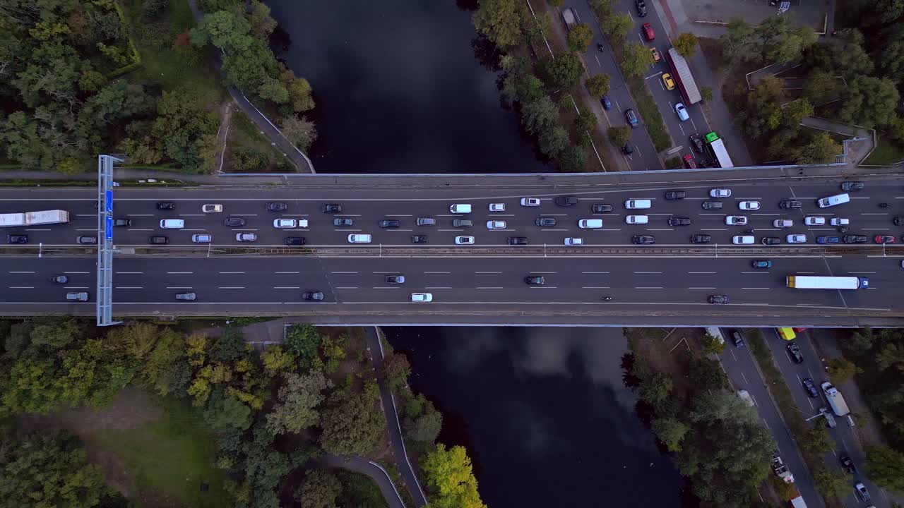 busy highway traffic crossing a bridge over a river surrounded by trees. Amazing aerial view flight descending drone top down Above view