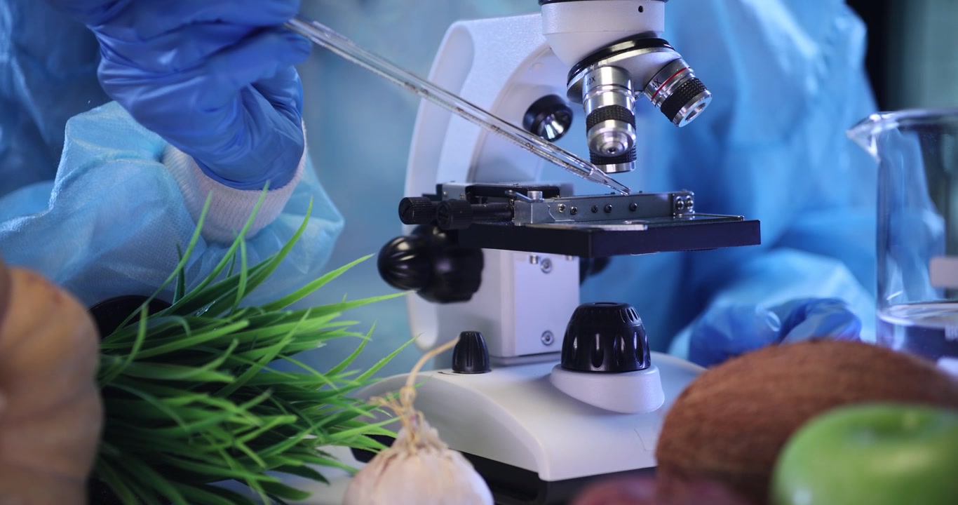 Un tecnico di laboratorio applica un liquido trasparente su un vetrino da microscopio pulito.