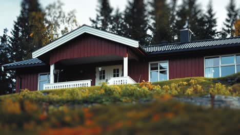 country house with a stone-tile roof in the autumn landscape in northern norway. a white bench stands on the porch.