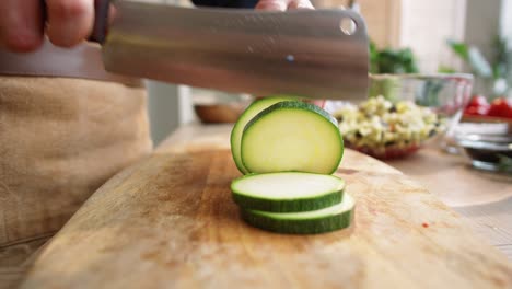 hands of male cook cutting zucchini into rounds