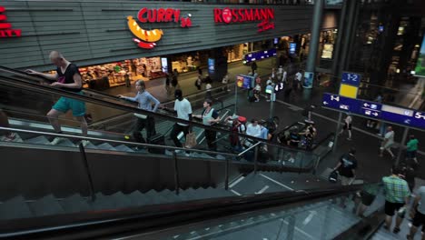 a bustling scene of people going down an escalator in berlin central station, capturing the dynamic atmosphere and architectural design of a busy transportation hub.