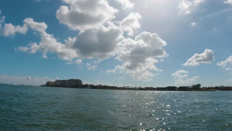 boat view of the shoreline of biscayne bay florida with the sun reflecting off the water