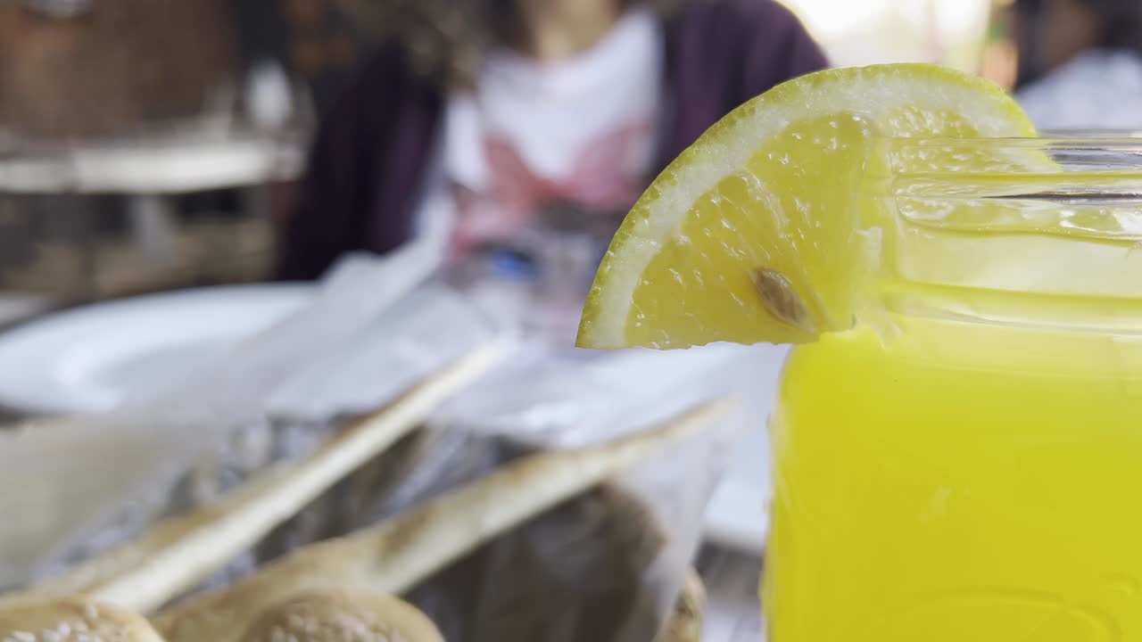 레몬 조각이 가장자리를 장식하는 신선한 레모네이드 한 잔, 멕시코의 흐릿한 레스토랑 설정에서, 활기차고 갈증을 해소하는 비디오를 만들고, 느린 동작 촬영