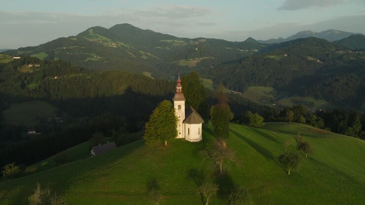 St Thomas Church in Slovenia sits on a hill at sunrise with stunning mountain views