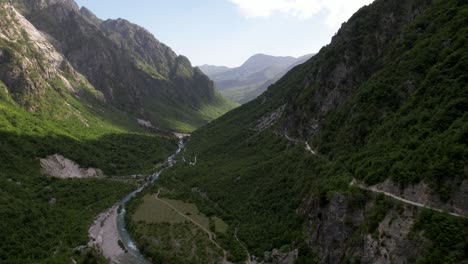 valle de thethi en albania, río que fluye a través de las altas montañas de los alpes cubiertas de vegetación verde y exuberante
