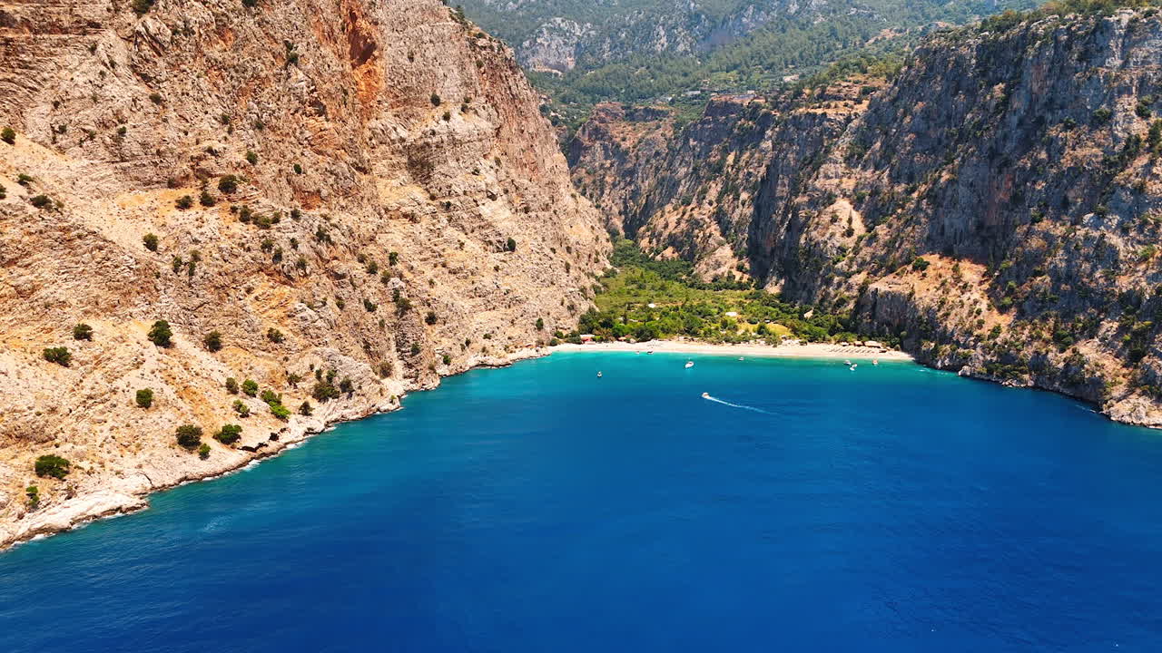 Calm blue waterscape of the Mediterranean Sea surrounded by stunning mountains. Approaching some boats near the sandy beach. Antalya, Turkey