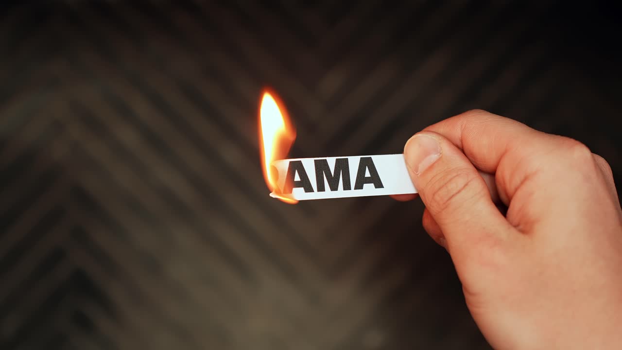 Primo piano di una mano che tiene una striscia di carta con scritto “DRAMMA” mentre il bordo prende fuoco, a simboleggiare la fine di pettegolezzi, conflitti e negatività, con spazio vuoto per il testo.