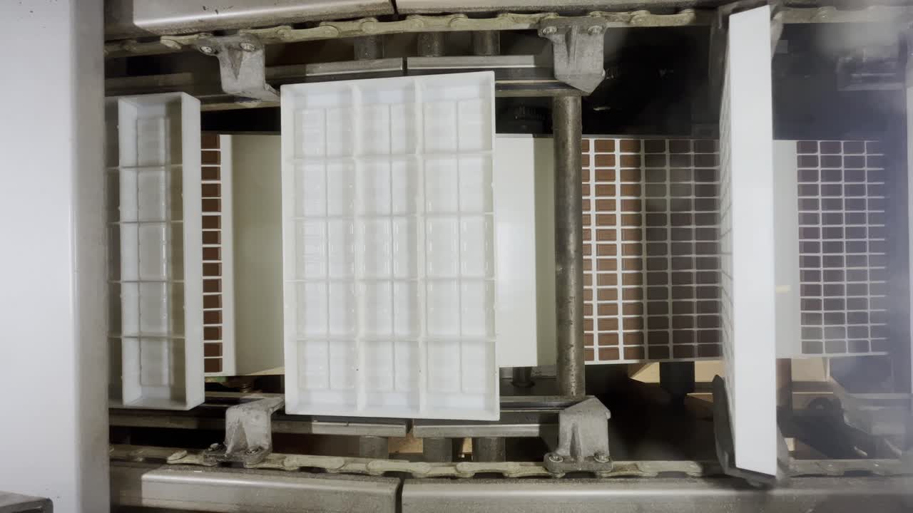 백색 플라스틱 모형은 공장에서 조립 라인에서 공장에서 작은 초콜릿 가게를 생산했습니다.