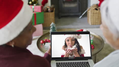 diversas amigas mayores que usan una computadora portátil para una videollamada de navidad con una mujer feliz en la pantalla