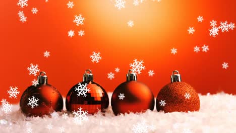 animación de bolas rojas de navidad y nieve cayendo sobre un fondo rojo