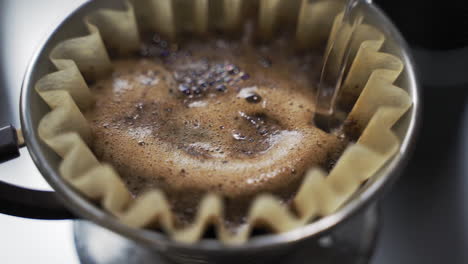 slow motion pouring hot water over freshly ground coffee beans on filter paper