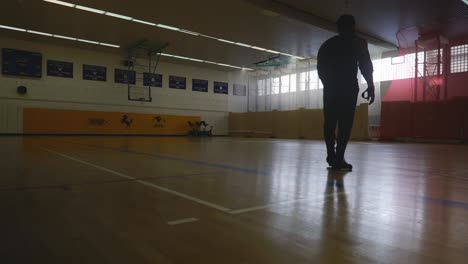 male walking onto court and looking a wall above - strong athletic muscular black man standing on basketball court looking around in 4k