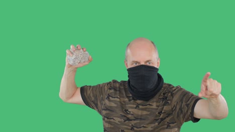 revolutionary in bandana menacing stone on rebellion, green background. bald vandal with stone in hand at popular revolution. civil war and coup.