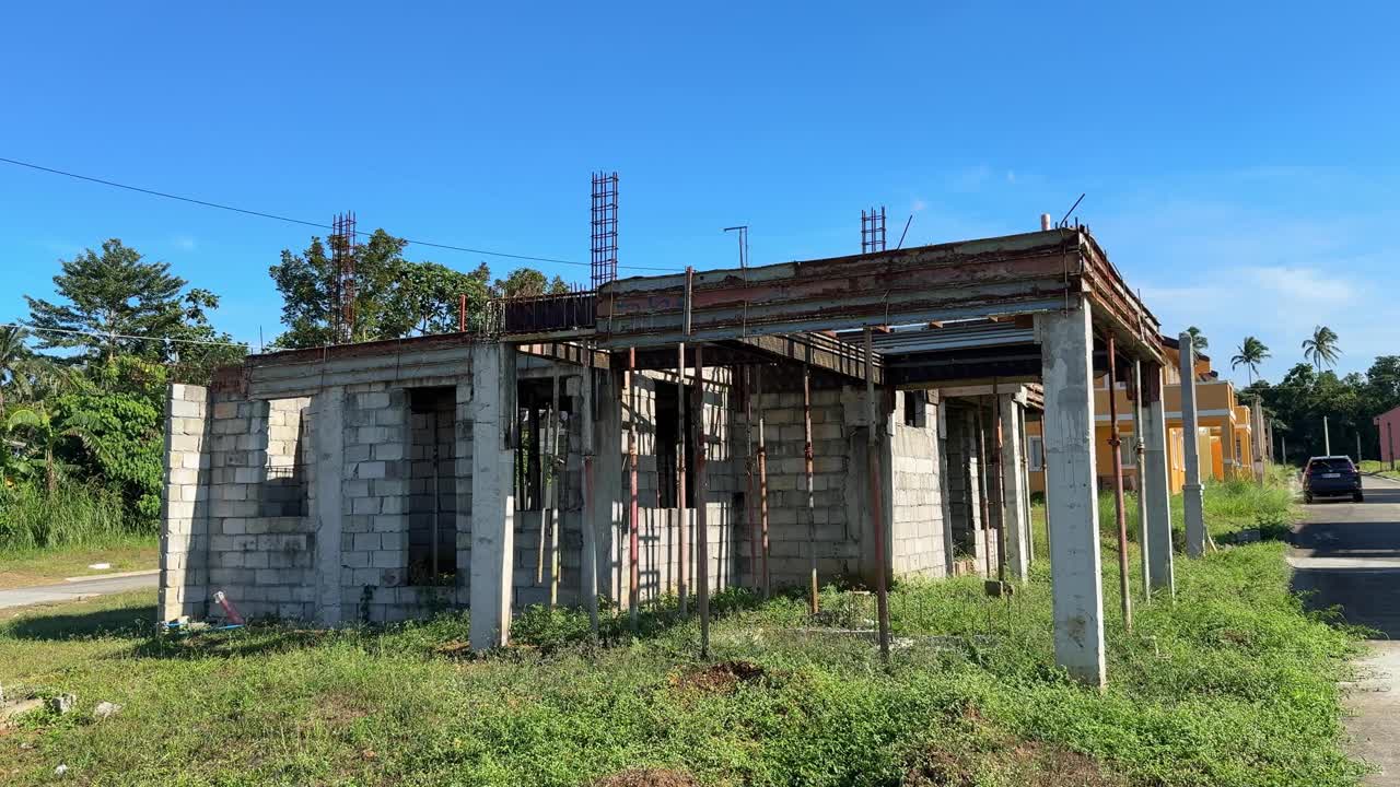 Ujęcie z poziomu gruntu przedstawiające aktywną budowę domów obok ukończonych rezydencji, symbolizujące rozwijające się osiedle mieszkaniowe. Camella Homes Alfonso Cavite Filipiny