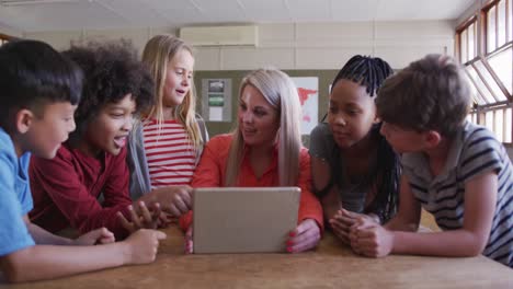 female teacher and group of kids using laptop in the class