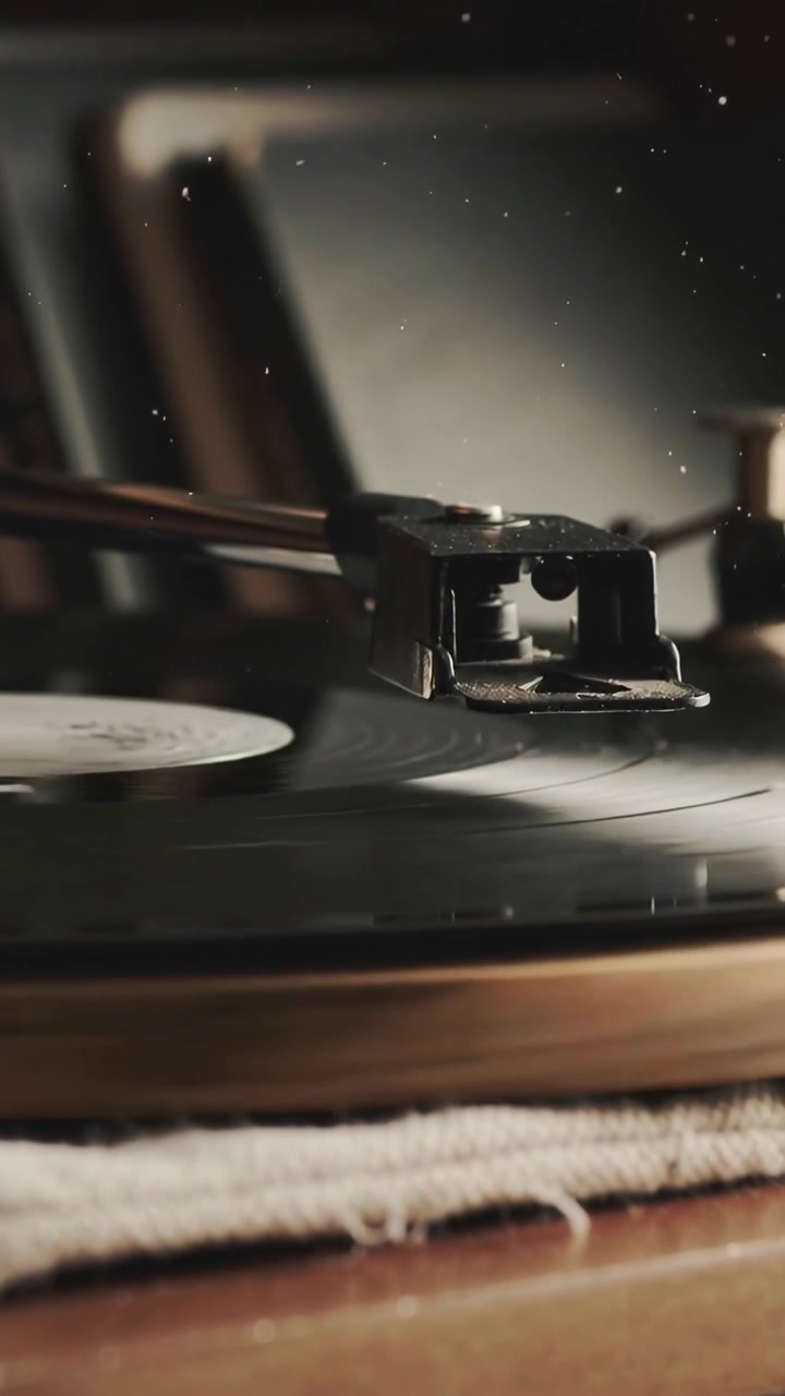Vertical video: Lowering tonearm and stylus as platter spins at home, playing vinyl record