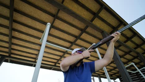un deportista dispara con una escopeta de doble cañón, un campo deportivo para una prueba de tiro está disparando a un esquete volador