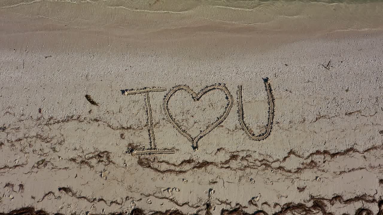 나는 모래에 쓰여진 u를 사랑하고 미친 감정으로 시계 방향으로 회전하는 것을 보여줍니다.