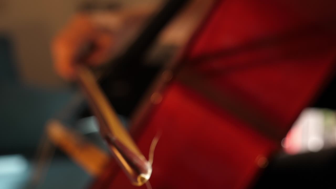 Primo piano di un archetto di violoncello che suona uno strumento a corda