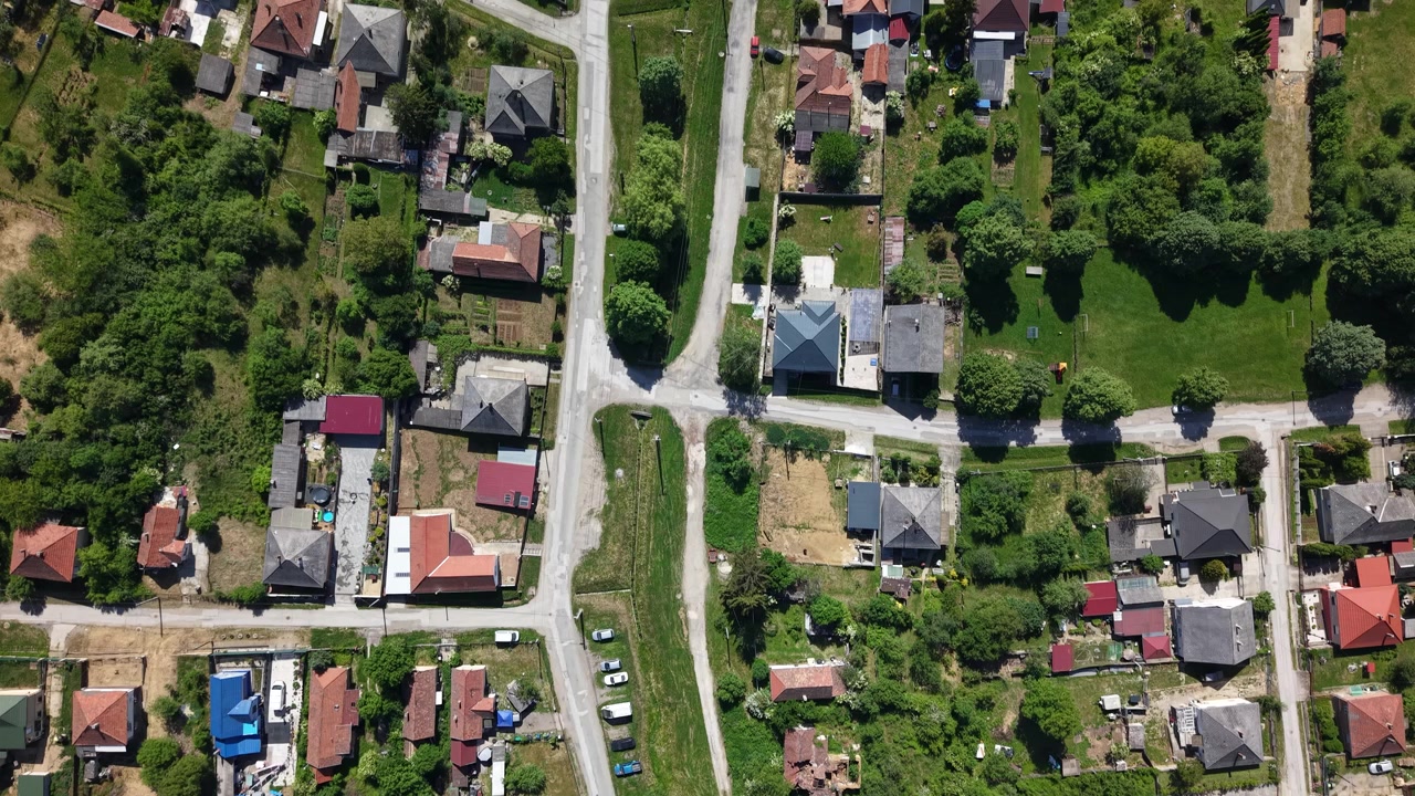 Una ripresa aerea con drone cattura un villaggio residenziale in Ungheria, mostrando case, strade e una vegetazione lussureggiante sotto la luce del giorno