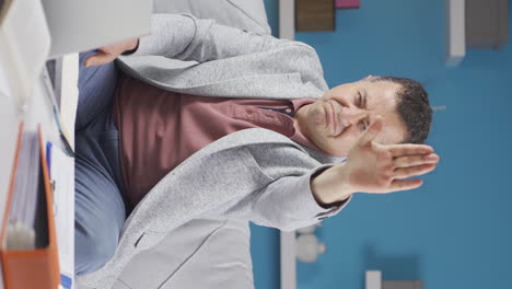 Vertical-video-of-Home-office-worker-old-man-says-stop-to-camera,-warns.