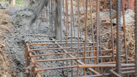 pouring concrete into building foundation trench with reinforced rebar