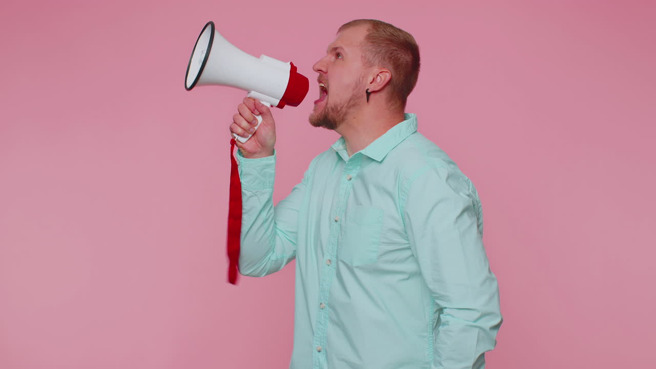 Smiling bearded man talking with megaphone, proclaiming news, loudly announcing sale advertisement