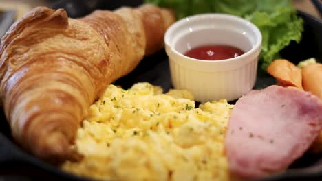 croissant, eggs, ham, and sauce on plate