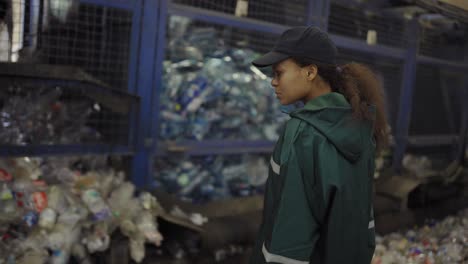 a young african-american woman checks a conveyor belt at a recycling plant. pollution control