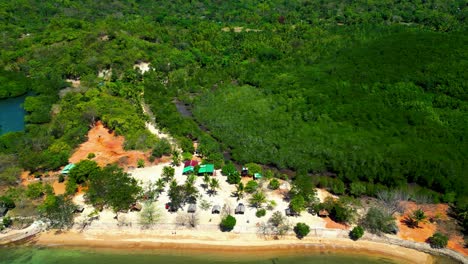 aerial view of tropical island beach with lush green forest and huts