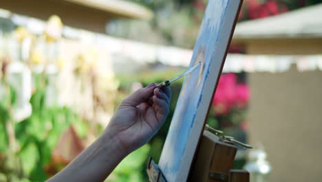 slow motion video of female artists hand painting on canvas with blurred background