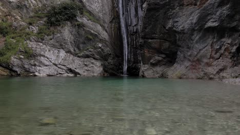 A-mountain-waterfall,-water-falling-from-a-steep-cliff-the-crystal-clear-lake