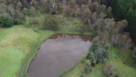 drone reversing over a rural property with ponds and some farm equipment