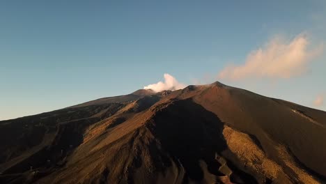 drone view of etna volcano on sicily, italy with smoke on a sunny day with a blue sky