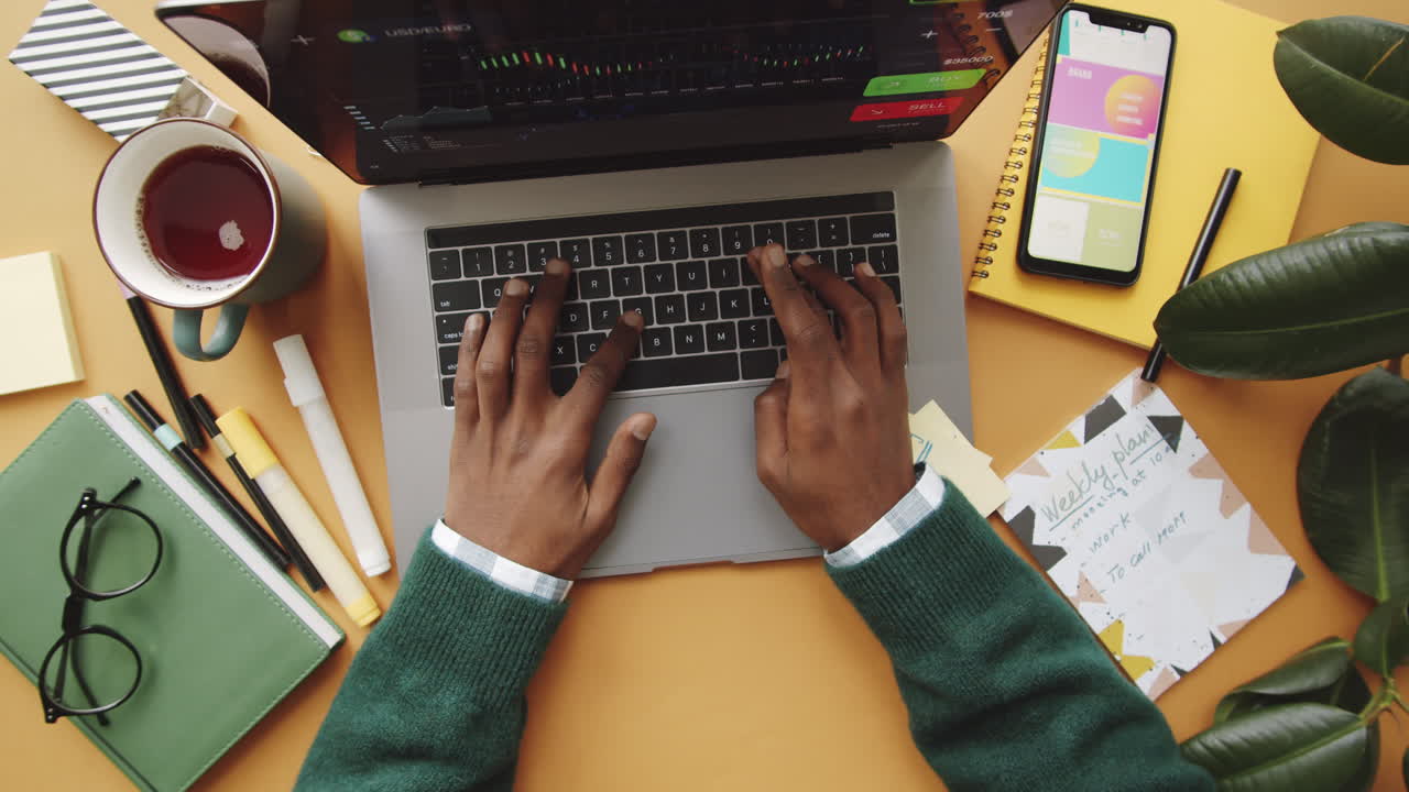 Persona che lavora a una scrivania con laptop, grafici di borsa e agenda