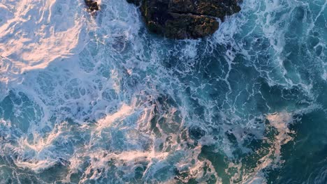 la jolla cove drone top down flyover bottom of frame to top waves crashing on rocks during golden sunrise light