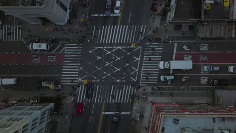 Aerial-birds-eye-overhead-top-down-ascending-footage-of-cars-driving-through-crossroads,-pedestrians-crossing-street-on--Manhattan,-New-York-City,-USA