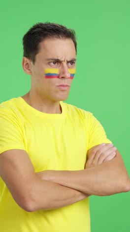 man with colombian flag painted looking away with serious expression