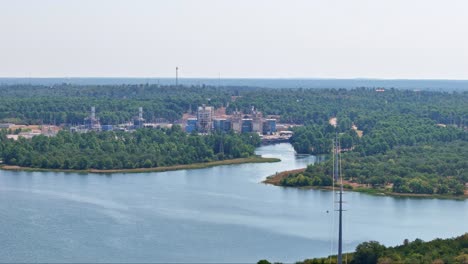 Moving-slowly-to-the-left-high-above-the-top-of-some-heavy-duty-power-lines-that-go-over-a-lake-to-a-power-plant-on-the-other-side-of-the-lake-which-has-an-inlet