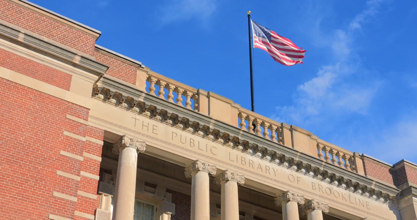 Bandiera degli Stati Uniti che sventola sul tetto dell'edificio della Biblioteca Pubblica di Brookline a Boston, Massachusetts, Stati Uniti. Angolazione bassa.