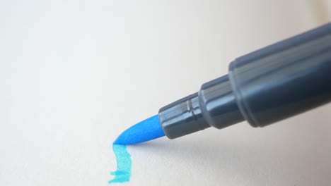 close-up of a blue marker pen drawing a line on white paper