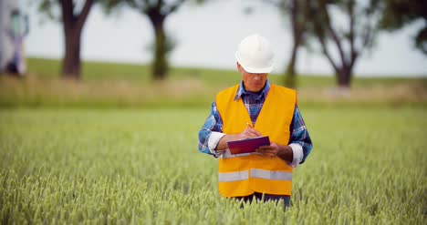 Engineer-Analyzing-Traffic-Polution-On-Clipboard-Amidst-Crops-At-Farm-7