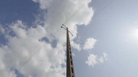 Clouds-pass-above-french-utility-pole-made-of-light-weight-concrete-cinderblocks