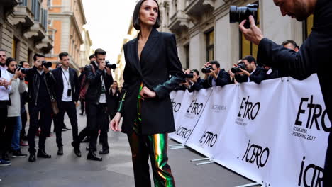 person in metallic pants at a fashion event surrounded by photographers