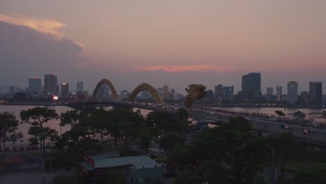 Time-lapse-of-iconic-landmark-Dragon-Bridge-Cau-Rong,-traffic-and-skyline-during-sunset-in-Danang,-Vietnam
