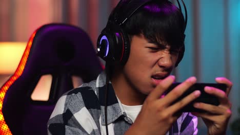 primer plano de un adolescente asiático serio jugando videojuegos en su teléfono inteligente